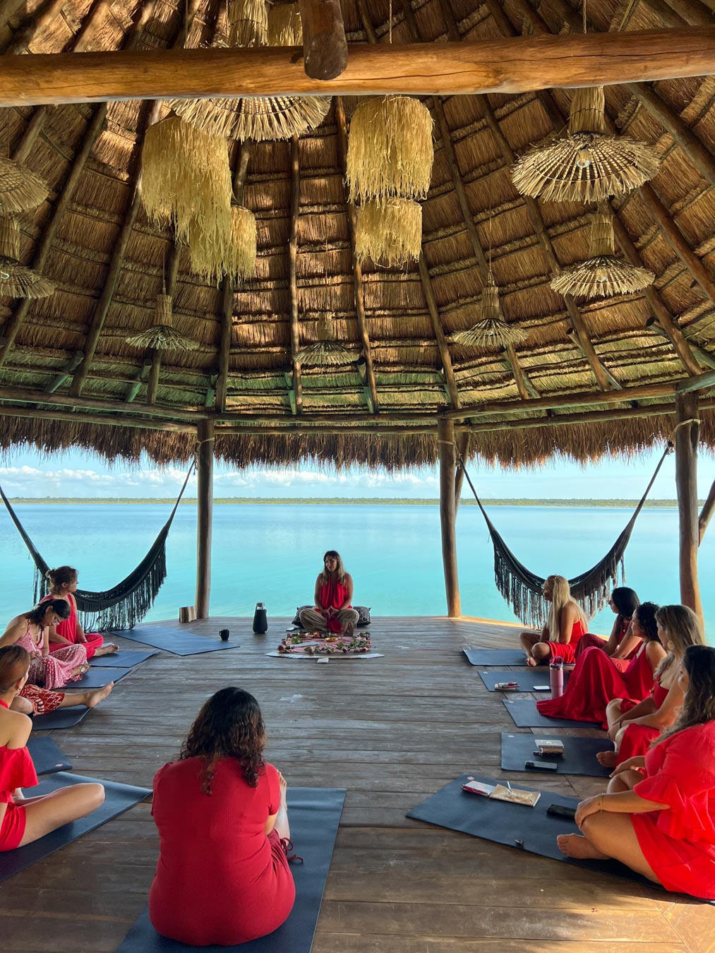 Women in red dresses sitting in a retreat circle by the water